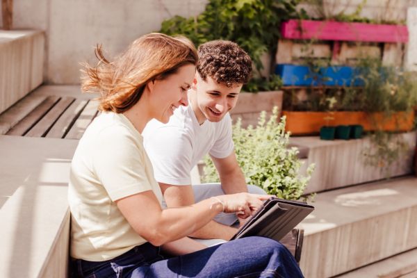 Beraterin zeigt einem Jugendlichen etwas auf einem Tablet